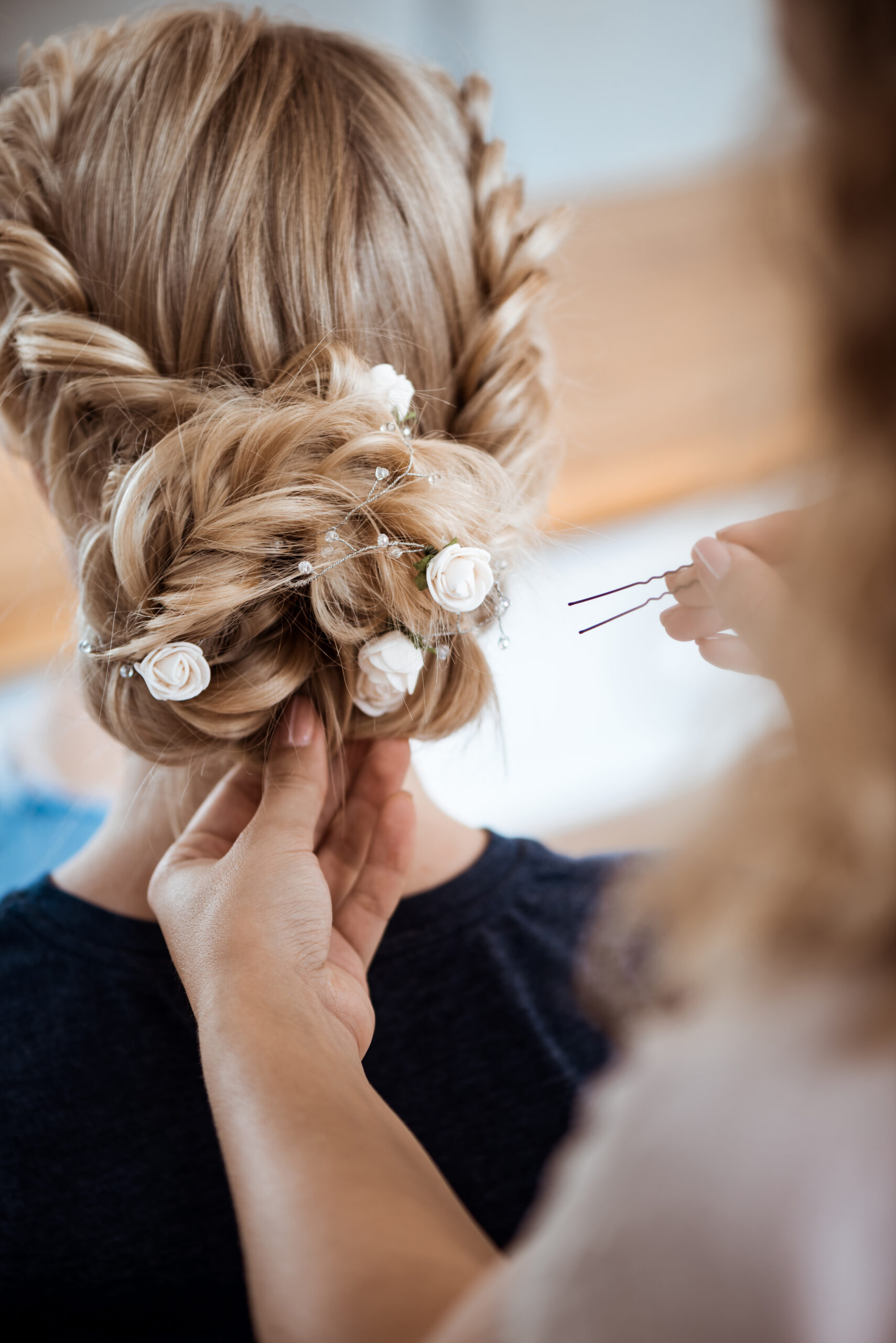 Female hairdresser making hairstyle to beautiful blonde girl in beauty salon. Copy space.